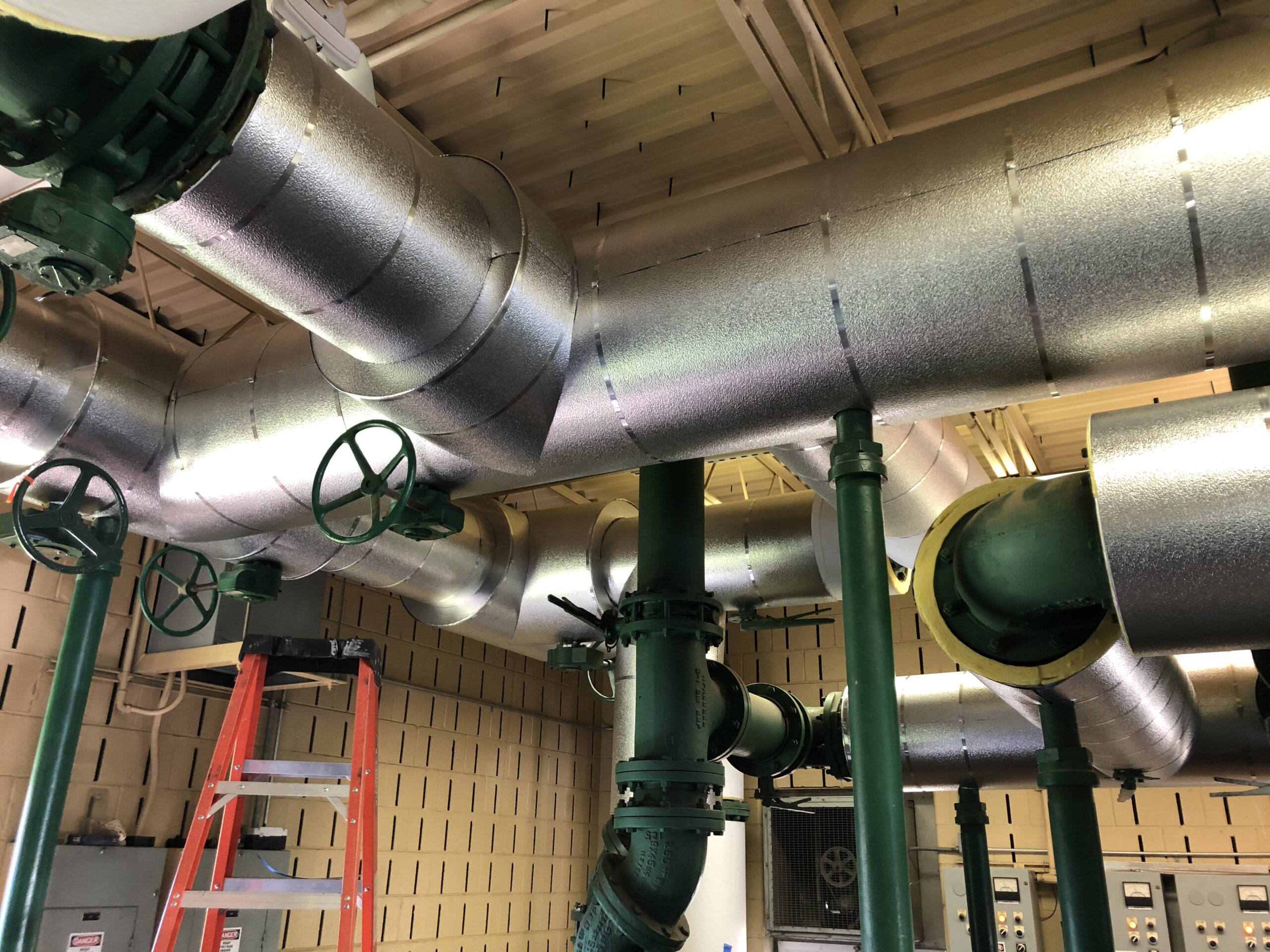 Newly installed mechanical insulation wrapped around pipes.