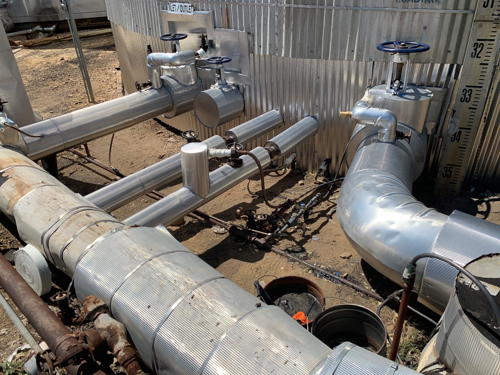 Industrial pipe insulation protecting pipes leading into a storage tank.